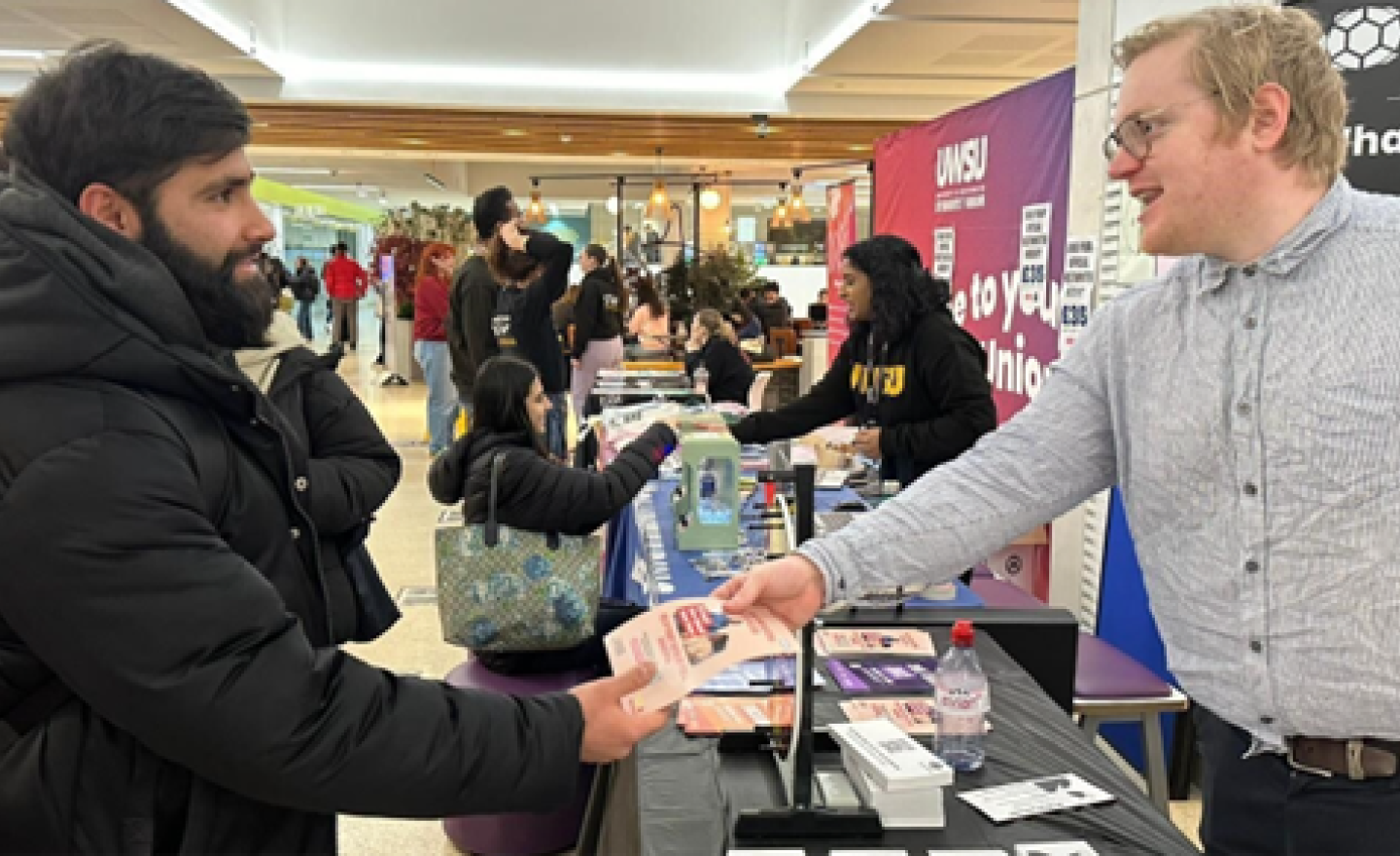 A man handing another man a leaflet.