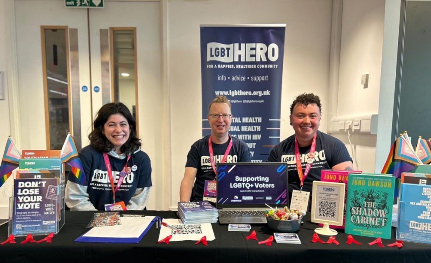 Three people sitting at an information desk for LGBTQ+ voters