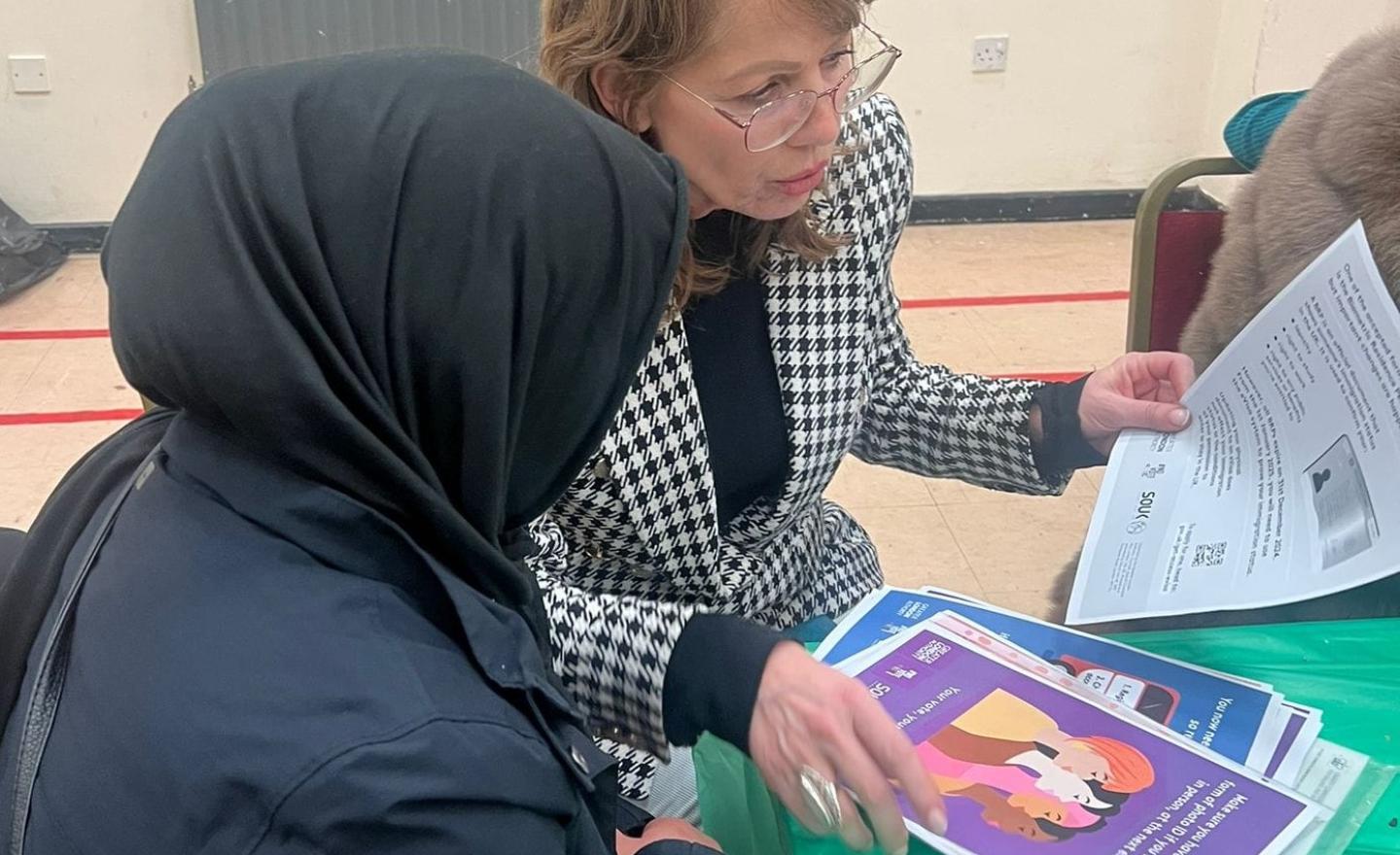 Two women, one talking to the other about registering to vote and civic and democratic participation