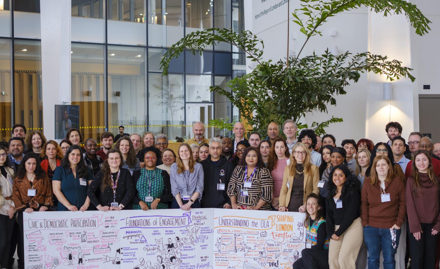 A group of people who attended the London Democracy Week event at City Hall holding boards created by the visual scribe