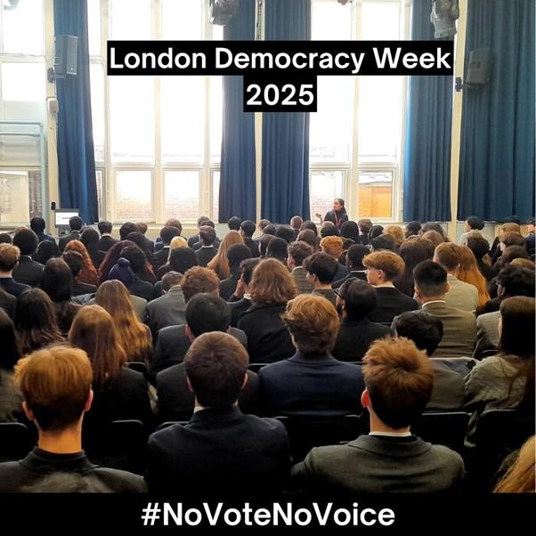 A group of students sitting in assembly with a presenter standing at the front sharing information about civic and democratic participation.