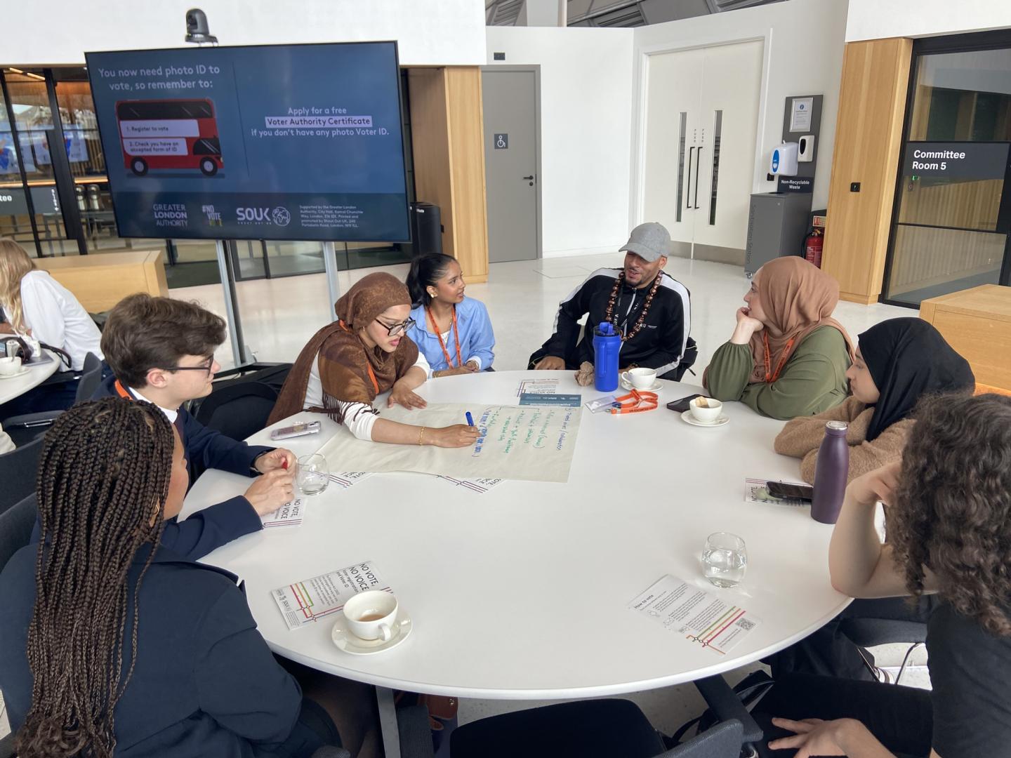 Group working together on a round table writing their ideas on a piece of flip chart paper