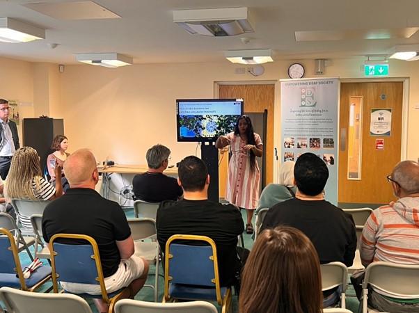 Person delivering civic and democratic participation workshop in BSL to a room of seated participants