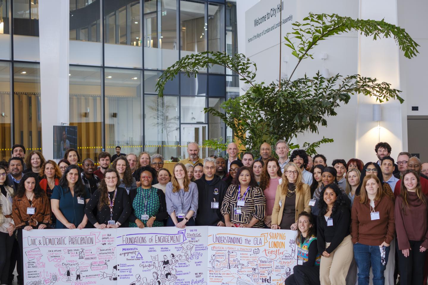 A group of people who attended the London Democracy Week event at City Hall holding boards created by the visual scribe