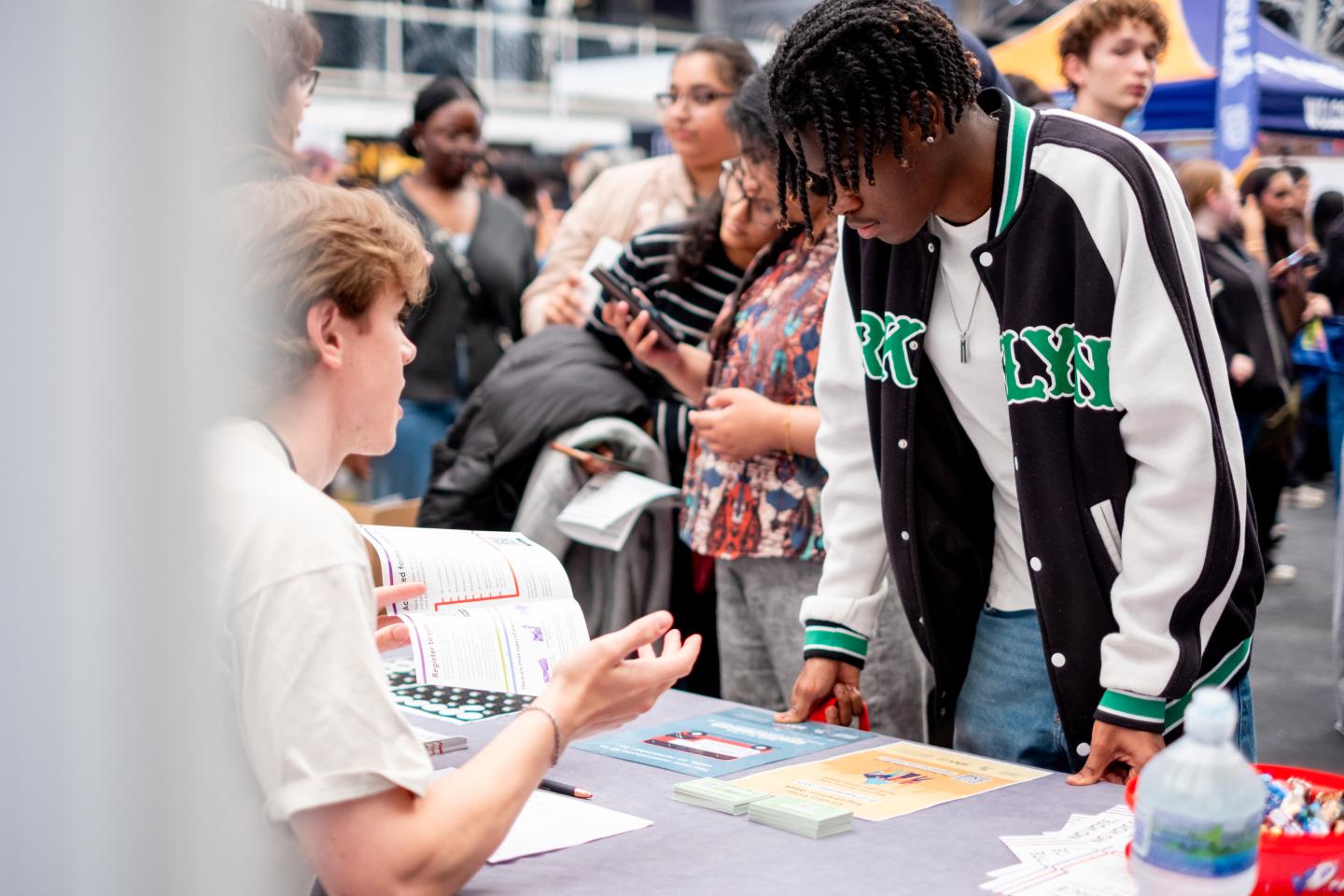 A student speaking to a person sat behind a voter registration stall
